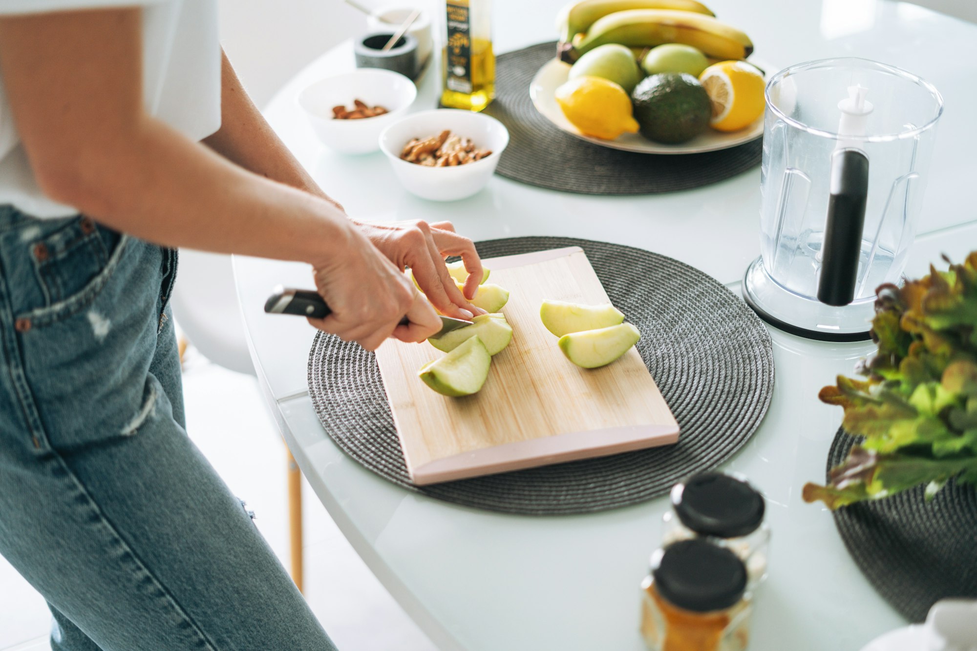 Young woman in white t-shirt cooking smoothie with apples healthy food in kitchen at home