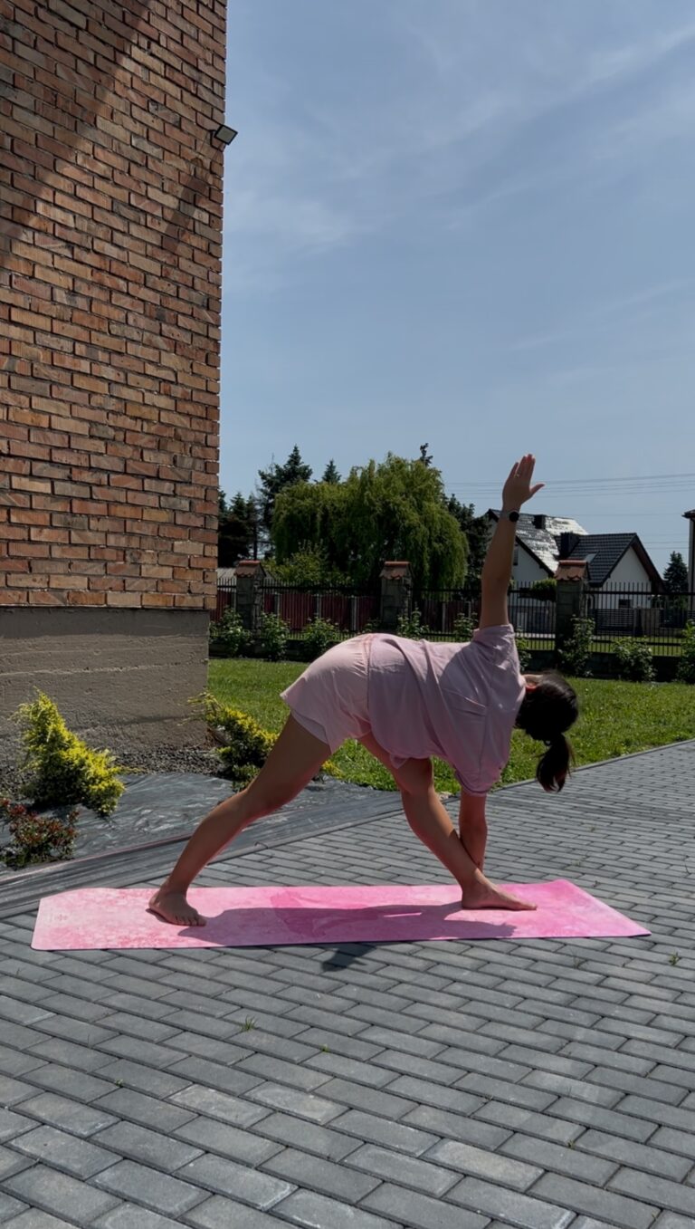 Autorka bloga wykonująca pozycję jogową Trikonasana - pozycja trójkąta w wersji odwróconej bardziej zaawansowanej