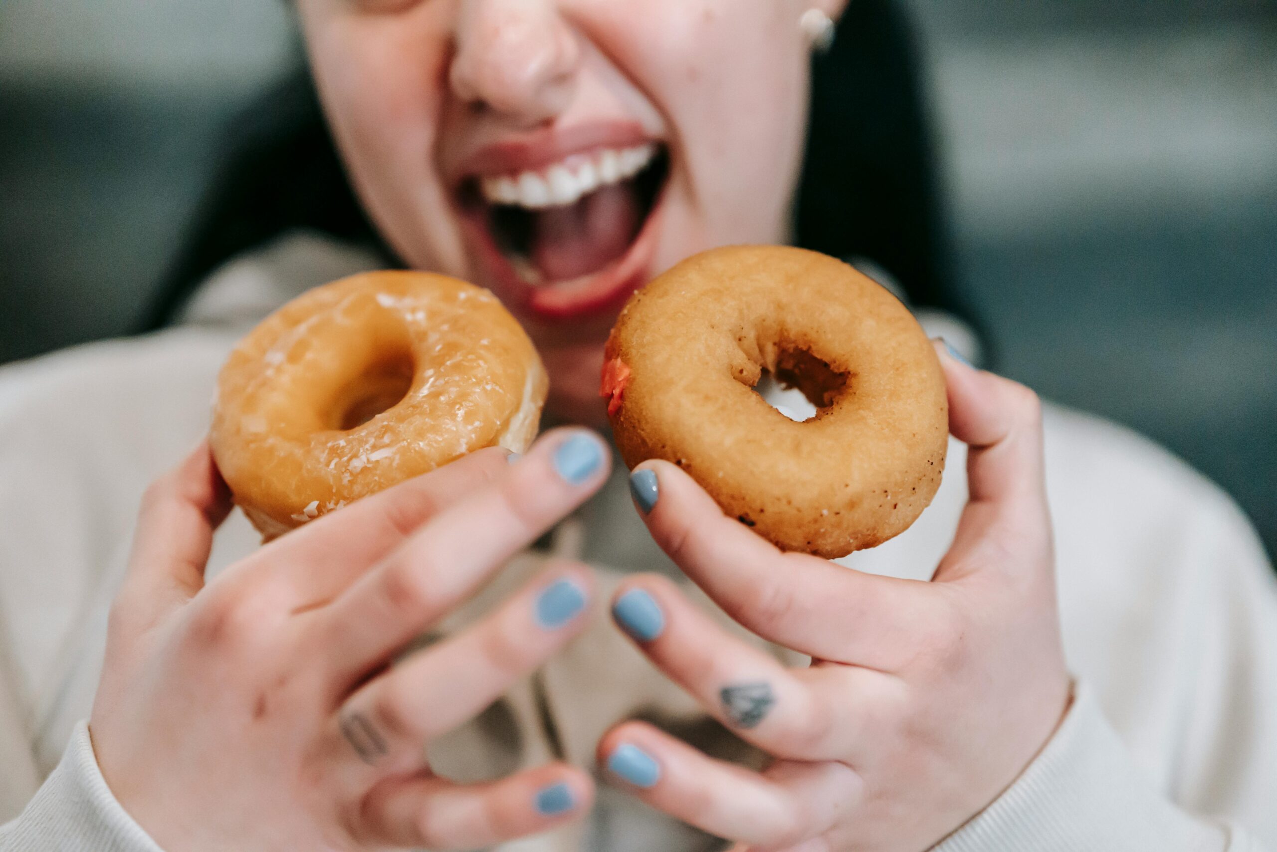 Kobieta trzymająca w obu rękach donuty